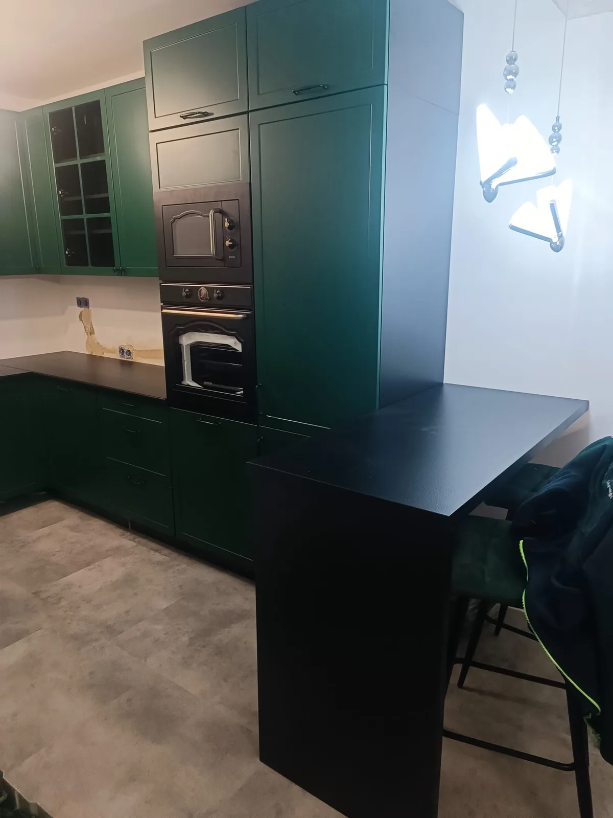 Dunkelgrüne Küche mit schwarzer Arbeitsplatte und Hochschrank mit Backofen