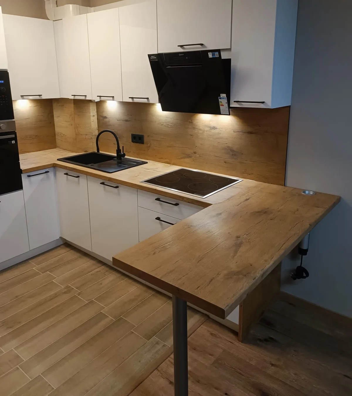 Weiße Küche mit Holzarbeitsplatte, schwarzer Spüle und Holztheke