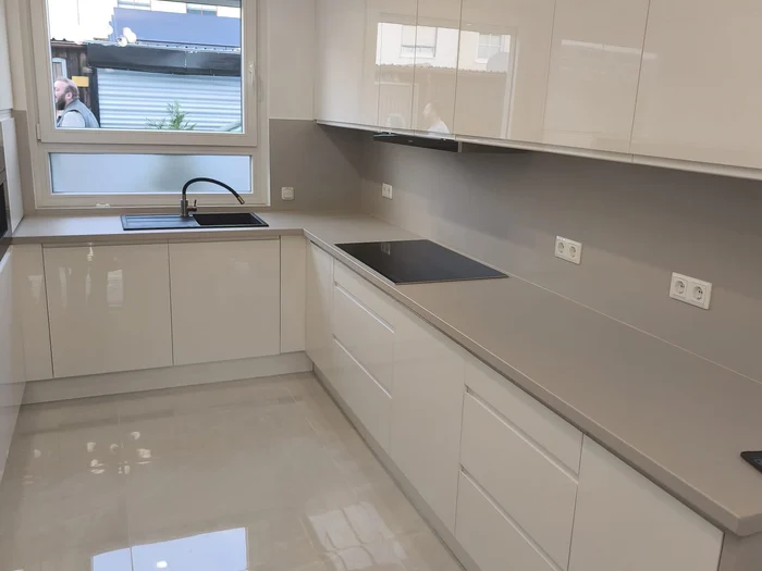 Gri tezgahlı, pencere altında evyeli ve ocaklı beyaz parlak mutfak